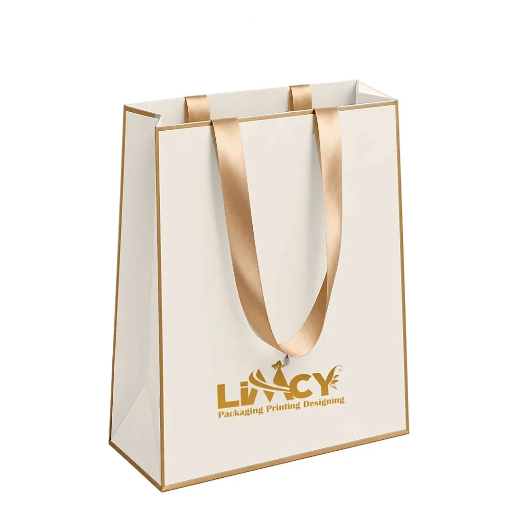 Small cream boutique paper bag with gold trim, satin ribbon handles, and gold logo
